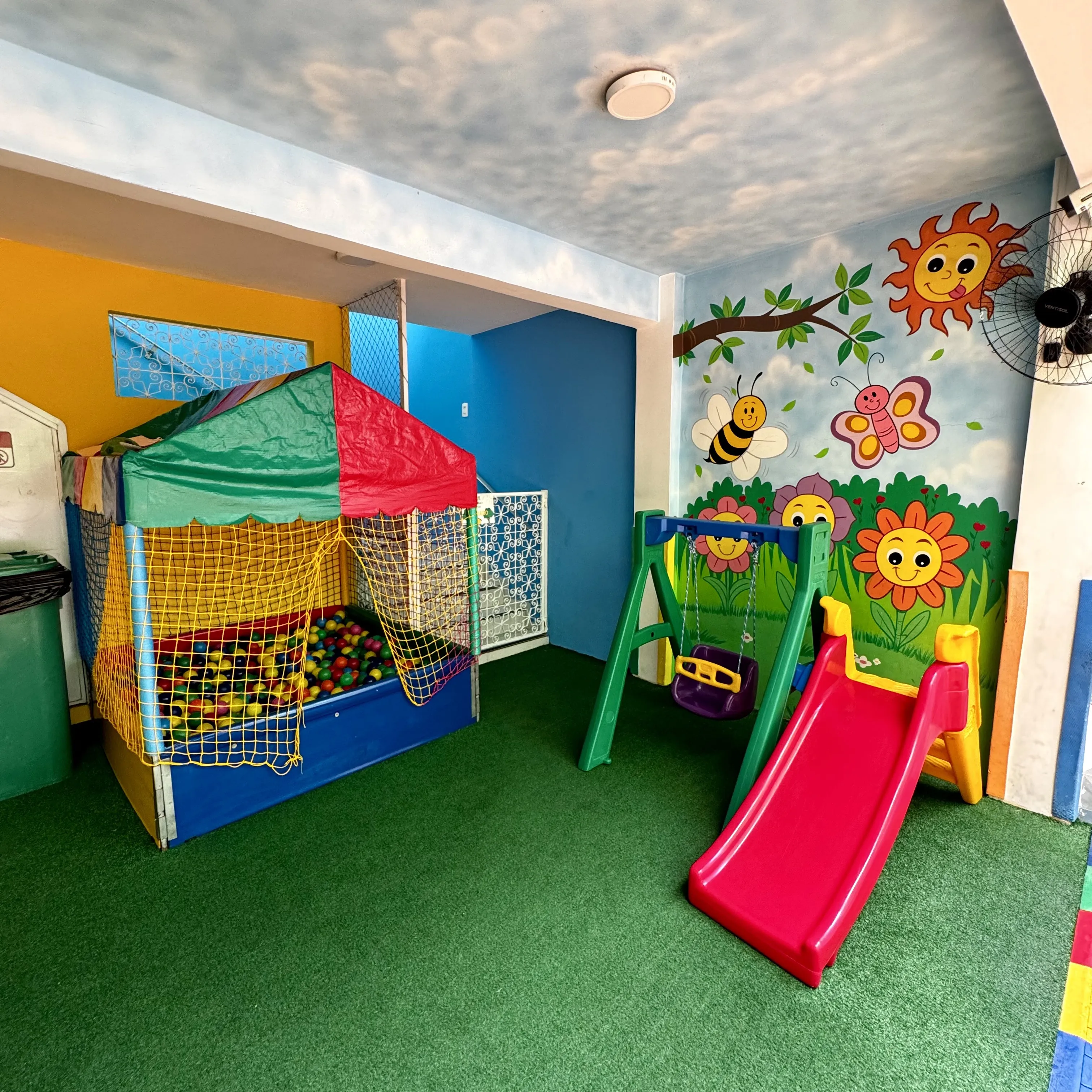 A tenda com a piscina de bolinhas e o balanço, no espaço coberto da escola